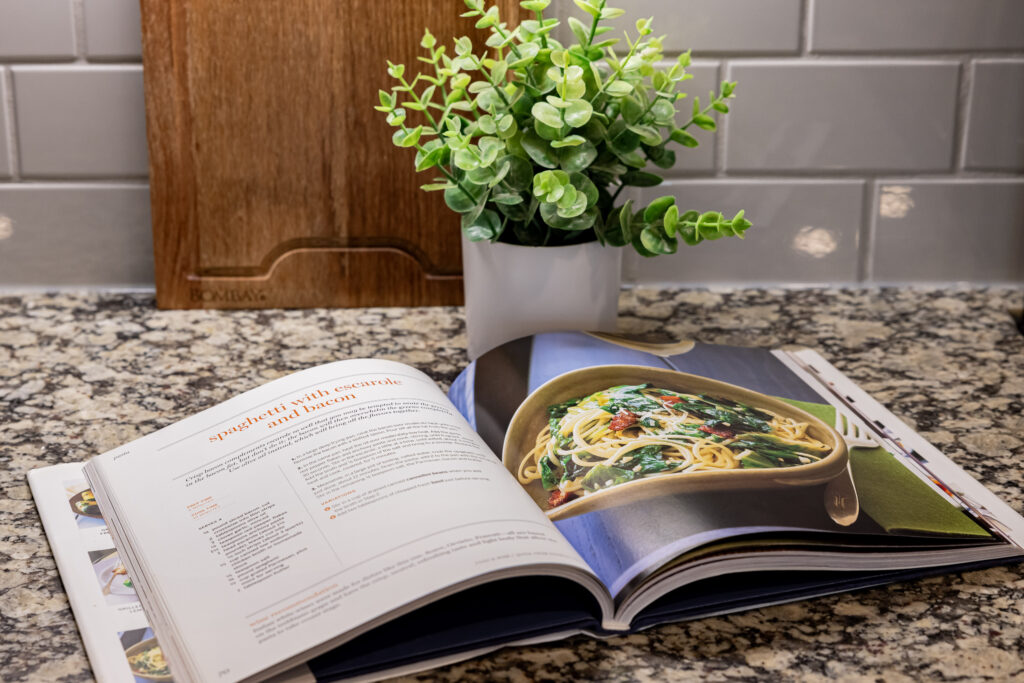 up close image of a cook book and plant on a kitchen counter