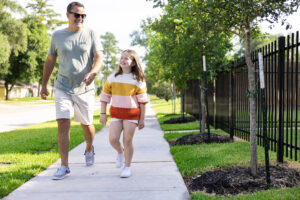 father and daughter walking on a sidewalk smiling