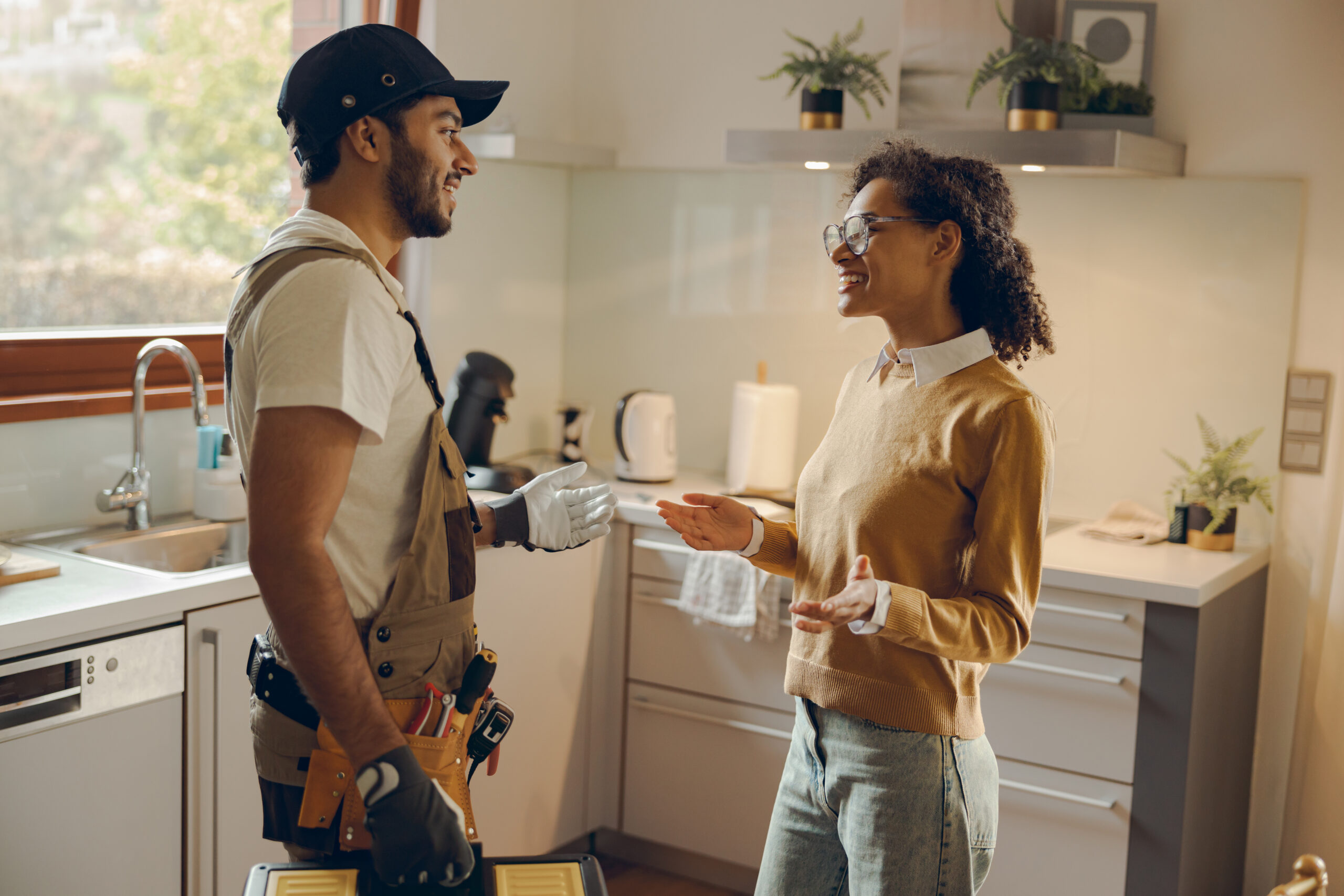 woman talking to male handyman while standing at the kitchen at home